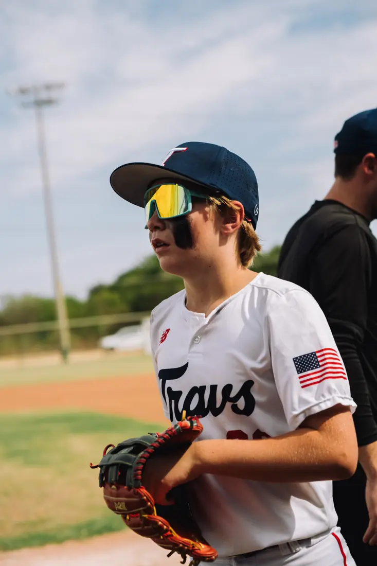 A high school Travelers player in a white jersey with his glove